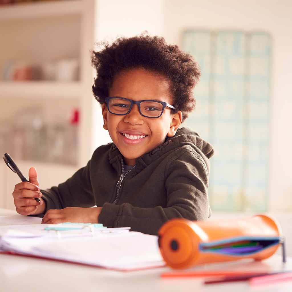 Young boy with glasses wearing a hoodie and writing