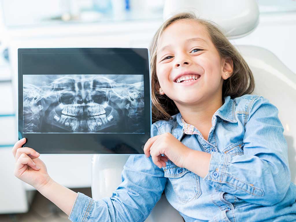 Girl smiling hold up an xray of her teeth